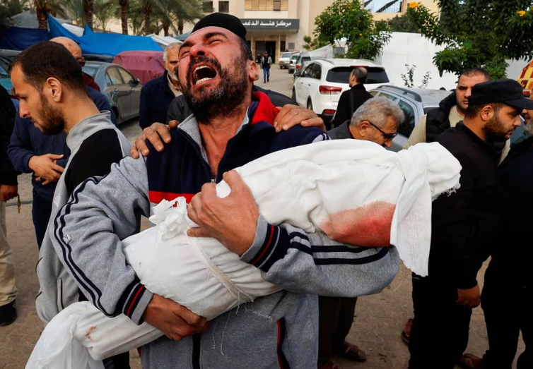 Seorang pria Palestina bereaksi saat membawa jenazah keponakannya Hanan Kaloob, yang tewas dalam serangan Israel, di rumah sakit Nasser di Khan Younis di selatan Jalur Gaza 22 November 2023. REUTERS/Mohammed Salem/File Foto Memperoleh Hak Lisensi
