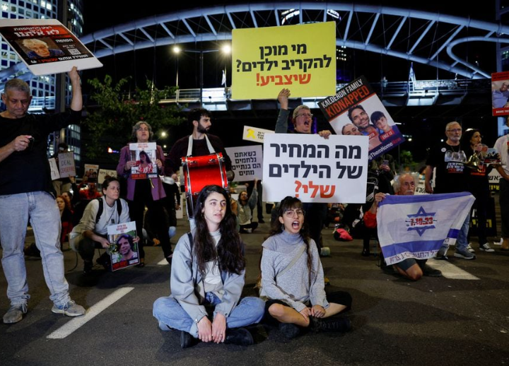 Orang-orang memegang poster selama demonstrasi yang diadakan untuk menuntut pembebasan sandera yang ditahan di Jalur Gaza setelah mereka ditangkap oleh kelompok bersenjata Hamas pada 7 Oktober, di Tel Aviv, Israel, 21 November 2023. REUTERS/ Amir Cohen Memperoleh Hak Lisensi