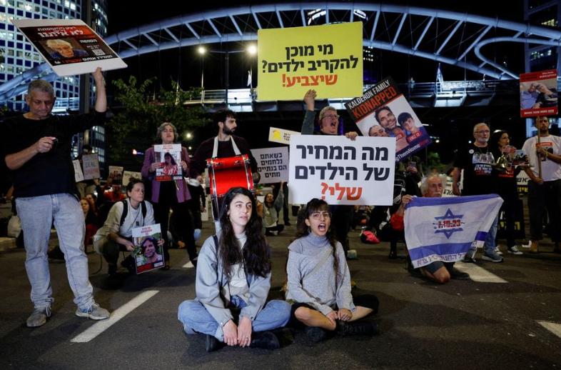 Orang-orang memegang poster selama demonstrasi yang diadakan untuk menuntut pembebasan sandera yang ditahan di Jalur Gaza setelah mereka ditangkap oleh kelompok bersenjata Hamas pada 7 Oktober, di Tel Aviv, Israel, 21 November 2023. REUTERS/ Amir Cohen Memperoleh Hak Lisensi
