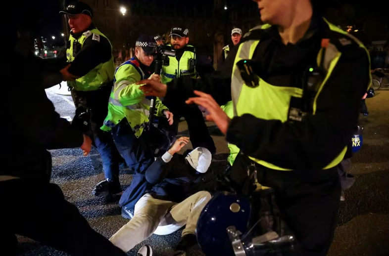 Petugas polisi menahan seorang pengunjuk rasa pada hari demonstrasi solidaritas dengan warga Palestina di Gaza, di tengah konflik yang sedang berlangsung antara Israel dan kelompok Islam Palestina Hamas, di London, Inggris, 11 November 2023. REUTERS/ Hannah McKay Memperoleh Hak Lisensi