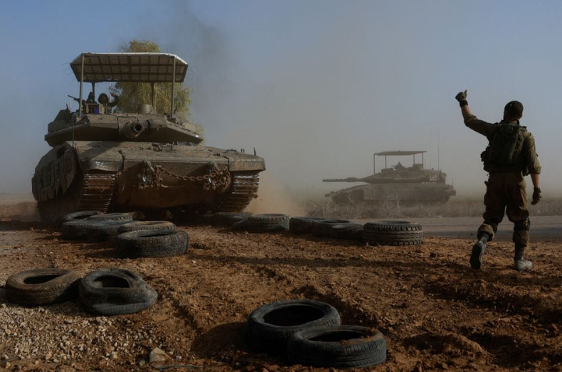 Seorang tentara Israel menunjuk ke arah awak tank saat melintasi jalan, sebagai bagian dari konvoi, di tengah konflik yang sedang berlangsung antara Israel dan kelompok Islam Palestina Hamas, dekat perbatasan Israel dengan Gaza selatan, di Israel, Desember 4, 2023. REUTERS/Amir Cohen Memperoleh Hak Lisensi