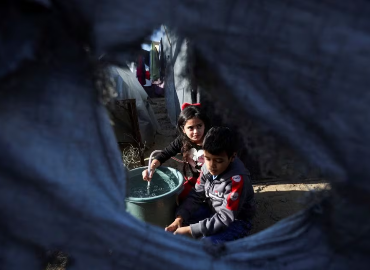 Anak-anak Palestina yang terlantar, yang meninggalkan rumah mereka akibat serangan Israel, berlindung di tenda kamp, ​​​​di tengah konflik yang sedang berlangsung antara Israel dan kelompok Islam Palestina Hamas, di Khan Younis di Jalur Gaza selatan, 11 Desember 2023 .REUTERS/Ibraheem Abu Mustafa Memperoleh Hak Lisensi